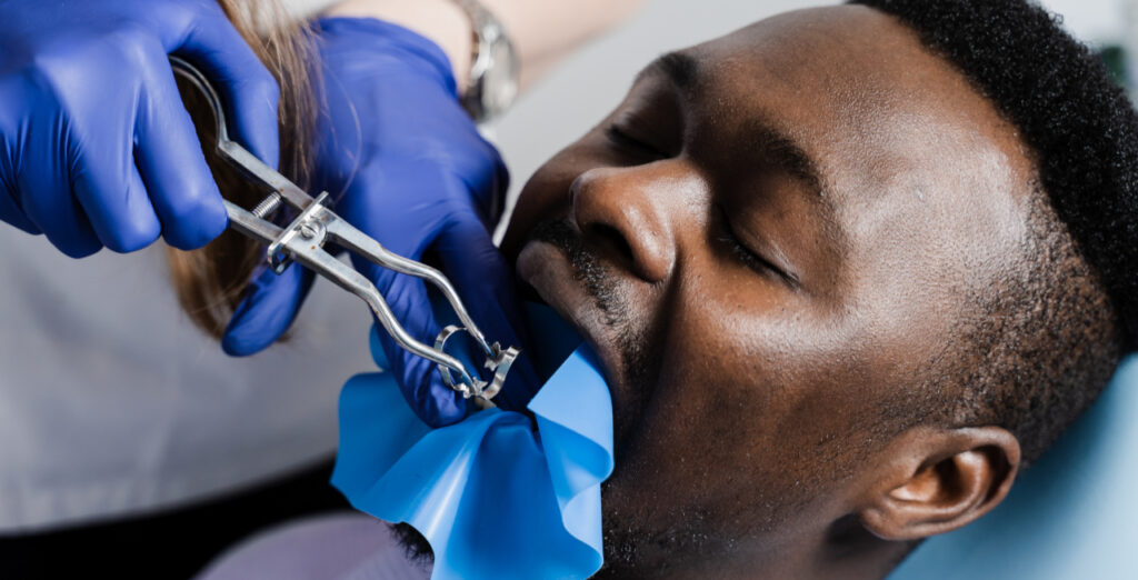 Male patient undergoing a tooth extraction performed by a dental professional