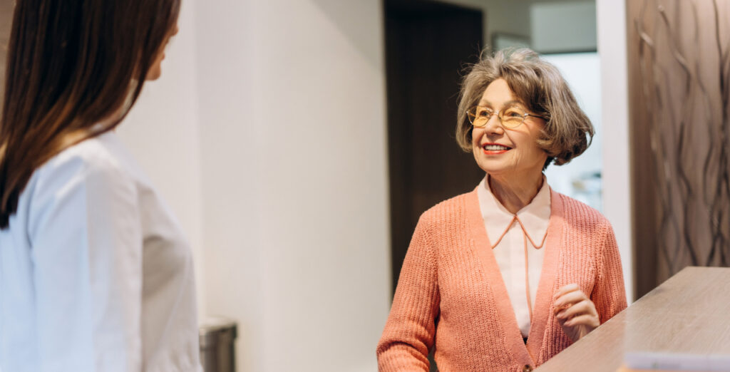 Senior Woman Speaking To Dentist At Reception
