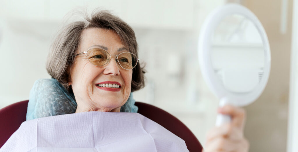 Smiling senior dental patient inspecting implants